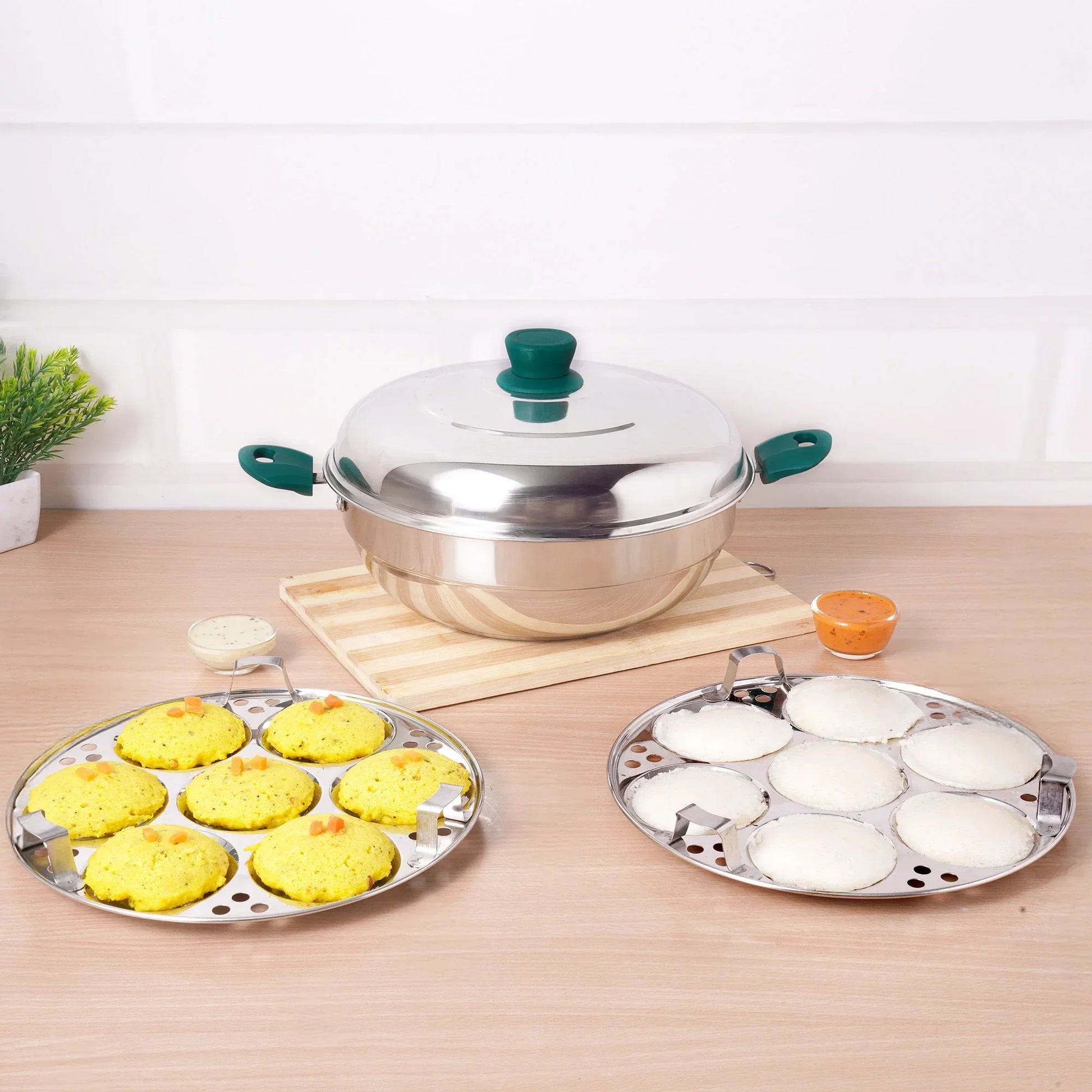 Stainless steel cookware set on a wooden surface with food items.