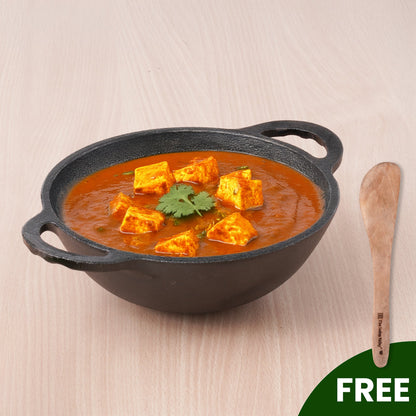 Black cast iron skillet with tofu curry on a beige background
