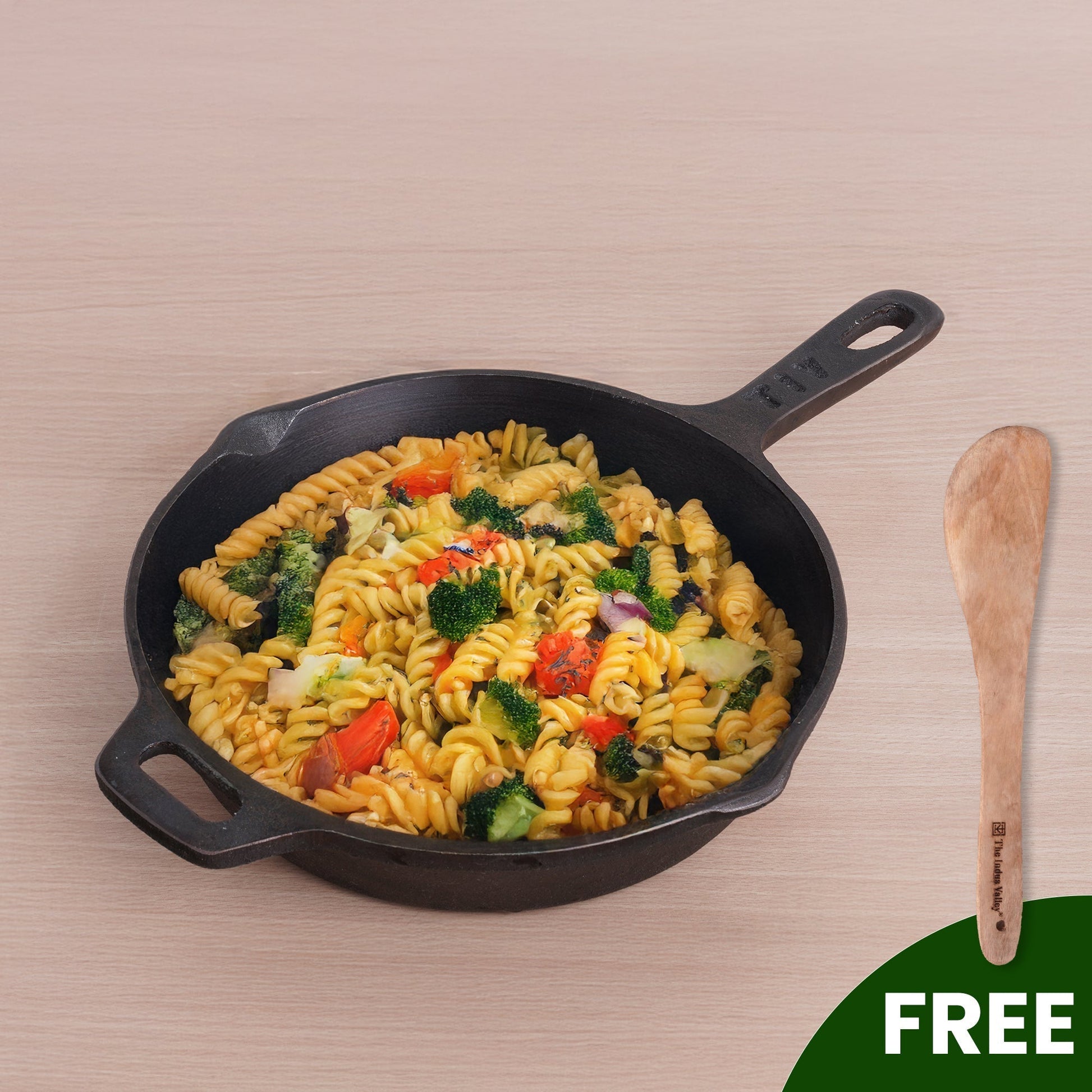 Black skillet with pasta and vegetables on a beige background