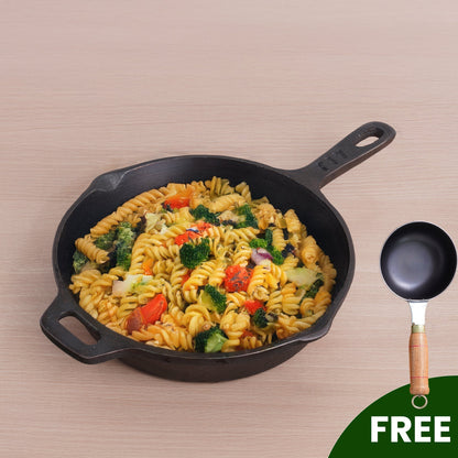Black cast iron skillet with pasta dish and a small frying pan on a beige background