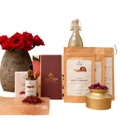 Collection of skincare and wellness products with a vase of red roses on a white background