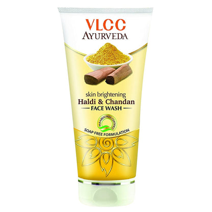 A plastic tube of VLCC Ayurveda skin brightening face wash with Haldi & Chandan. The packaging is chrome yellow with an illustration of turmeric and sandalwood and text detailing the product name and benefits.
