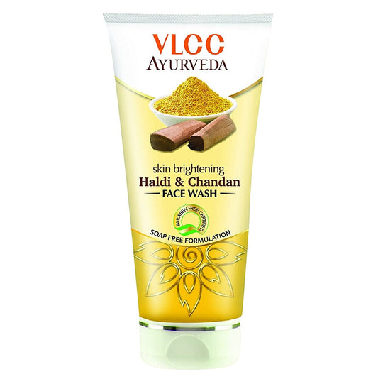 A plastic tube of VLCC Ayurveda skin brightening face wash with Haldi & Chandan. The packaging is chrome yellow with an illustration of turmeric and sandalwood and text detailing the product name and benefits.