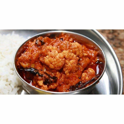 Bowl of cauliflower curry with rice on a metal tray