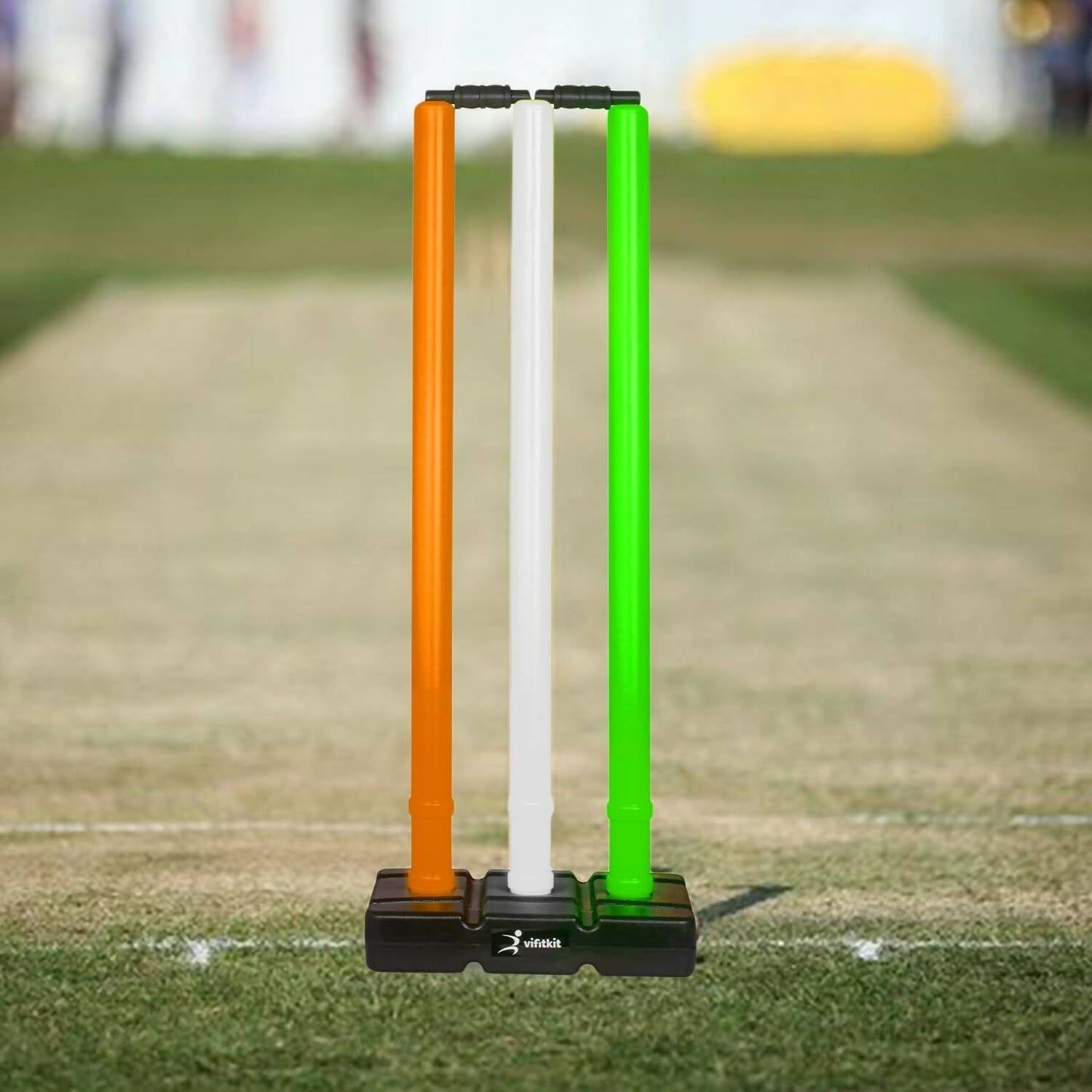 Three colorful cricket stumps on a grass field
