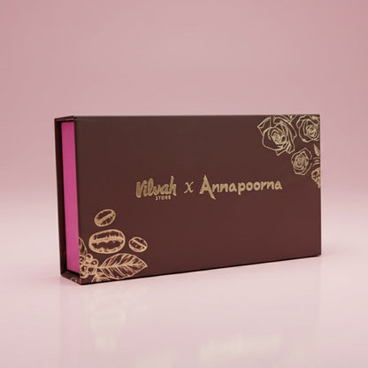 Brown box with gold branding and decorative elements on a pink background