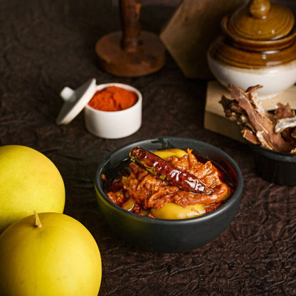 Bowl of spicy dish with yellow fruits and spices on a dark surface