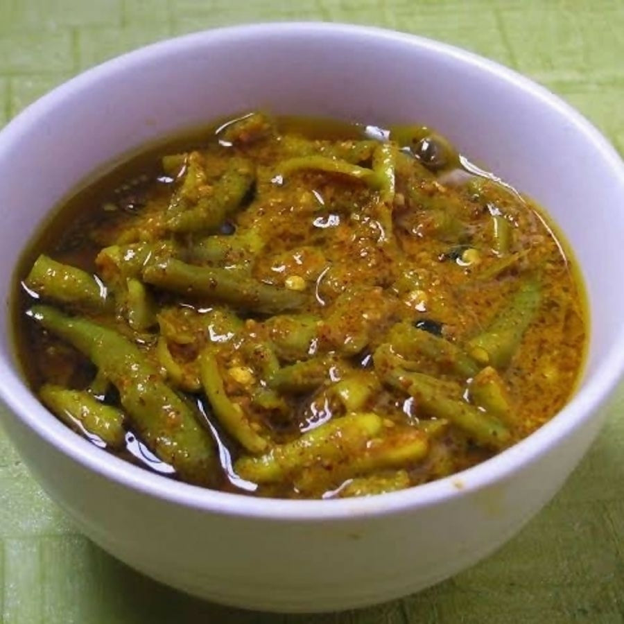 Bowl of green bean curry on a green background