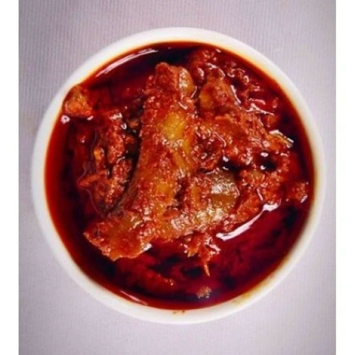 Reddish-brown food in a white bowl on a gray background