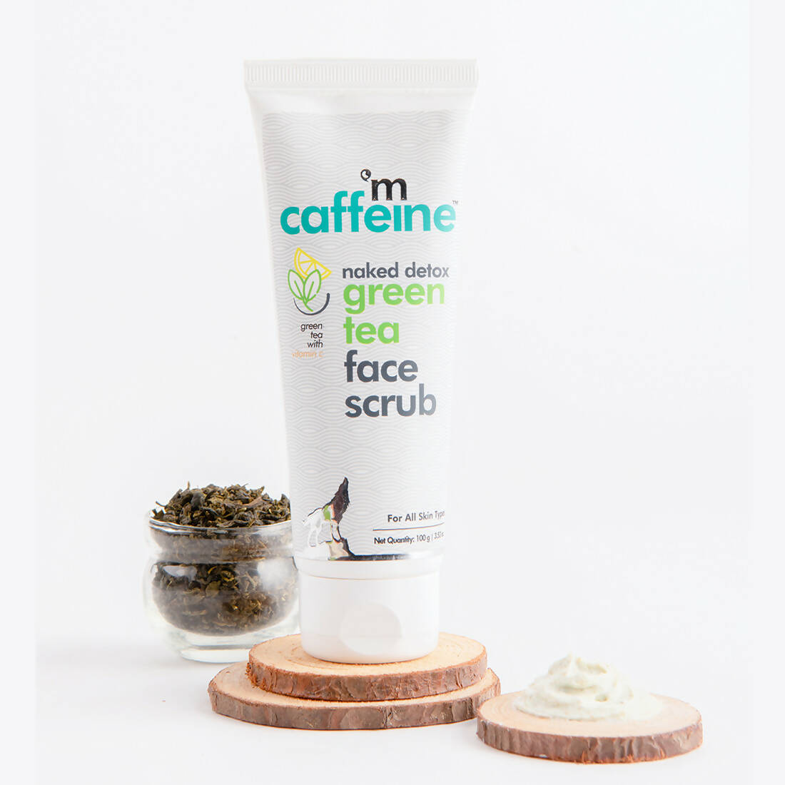 Caffeine naked detox green tea face scrub with a small container of green tea leaves on a white background