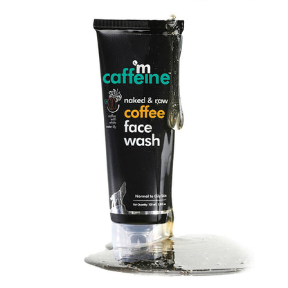 Black tube of 'm caffeine naked & raw coffee face wash' on a clear stand with a white background