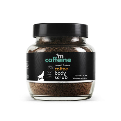 A glass jar containing mCaffeine Naked & Raw Coffee Body Scrub with a black lid and a label that includes the product name and a silhouette of a mountain.